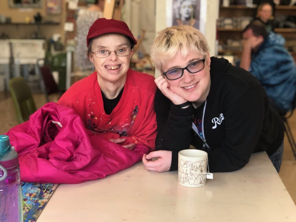 Two people leaning over a table and smiling at the camera