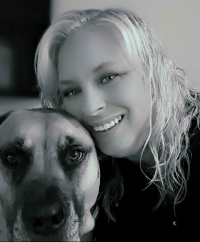 A black and white picture of a smiling person with their dog