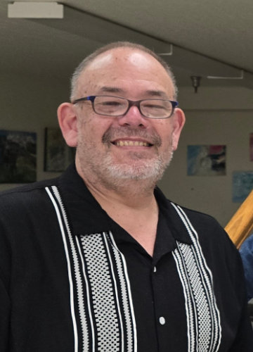 A smiling person in a nice shirt poses for the camera