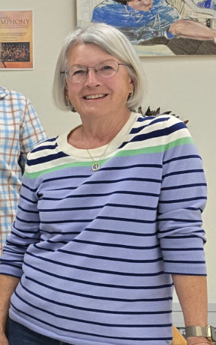 A person smiles and leans on a table